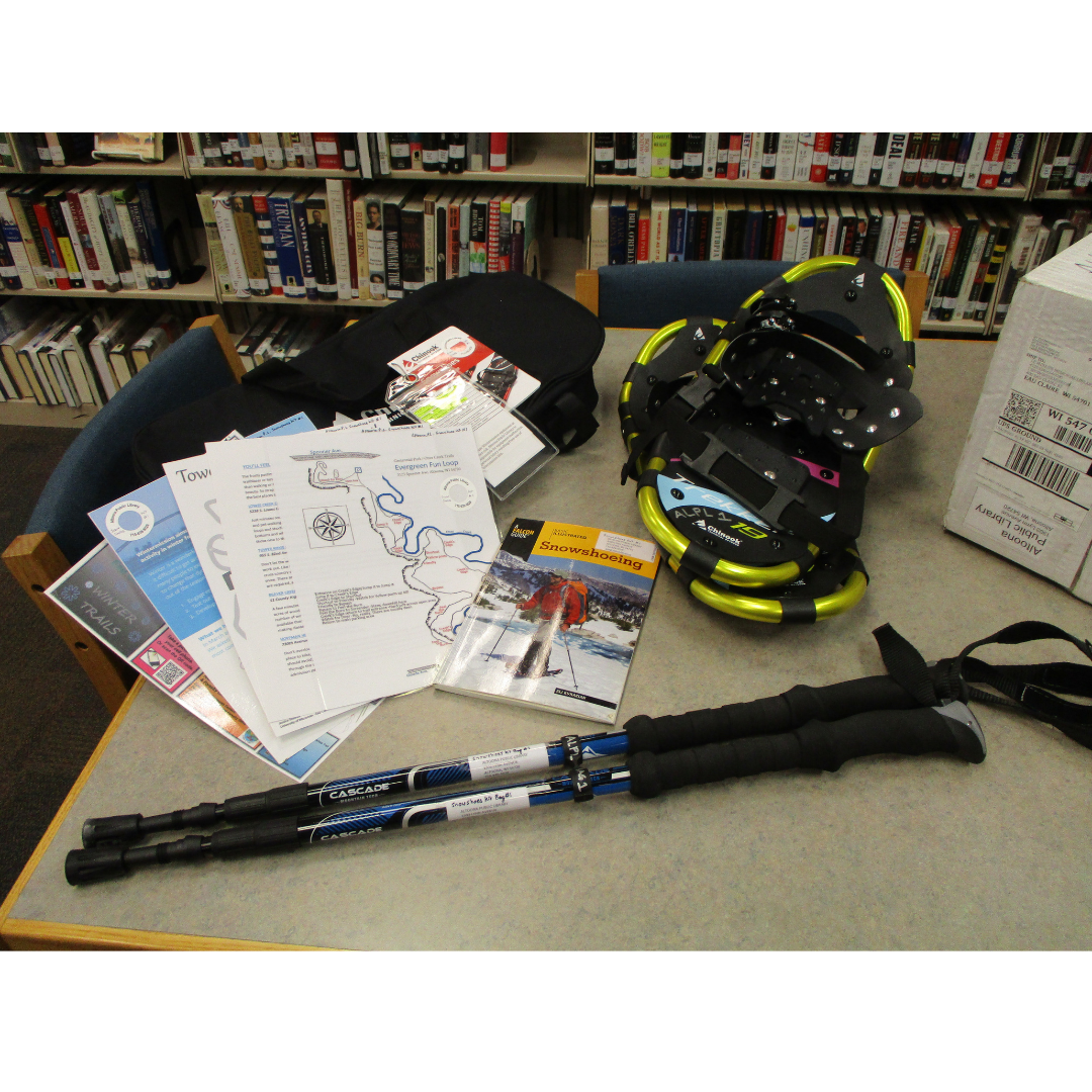 green and black snowshoes, two black and blue trekking poles, black bag and variety of maps spread out on table